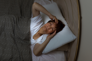 Senior woman awake at night in bed, related to sleep issues in elderly, Milton, WI
