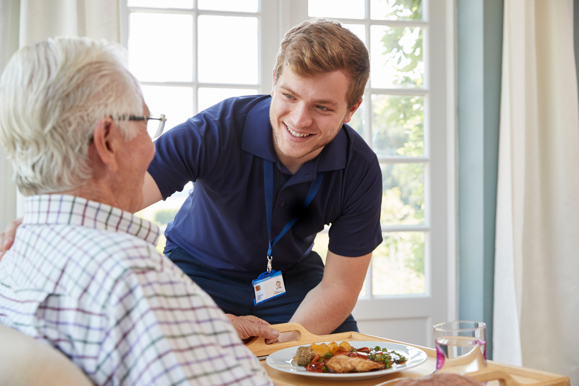 Caregiver serving meal to senior resident at an assisted living facility in Milton, Wisconsin – Resources for Assisted Living Facilities.