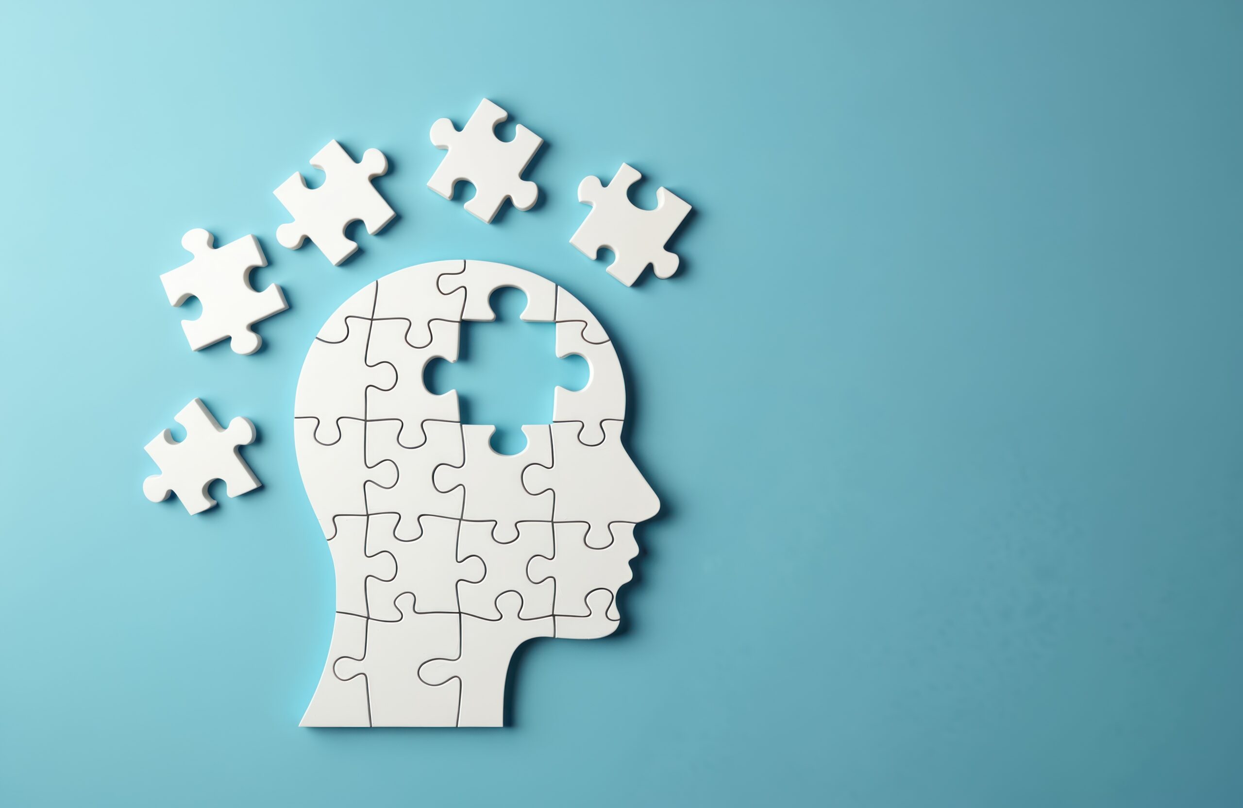 Puzzle head with missing elements on blue background. Trauma, loss. Stroke, brain disorders memory problems, dementia, mind, mental issues. Thinking, intelligence, piece of mind, alzheimer disease