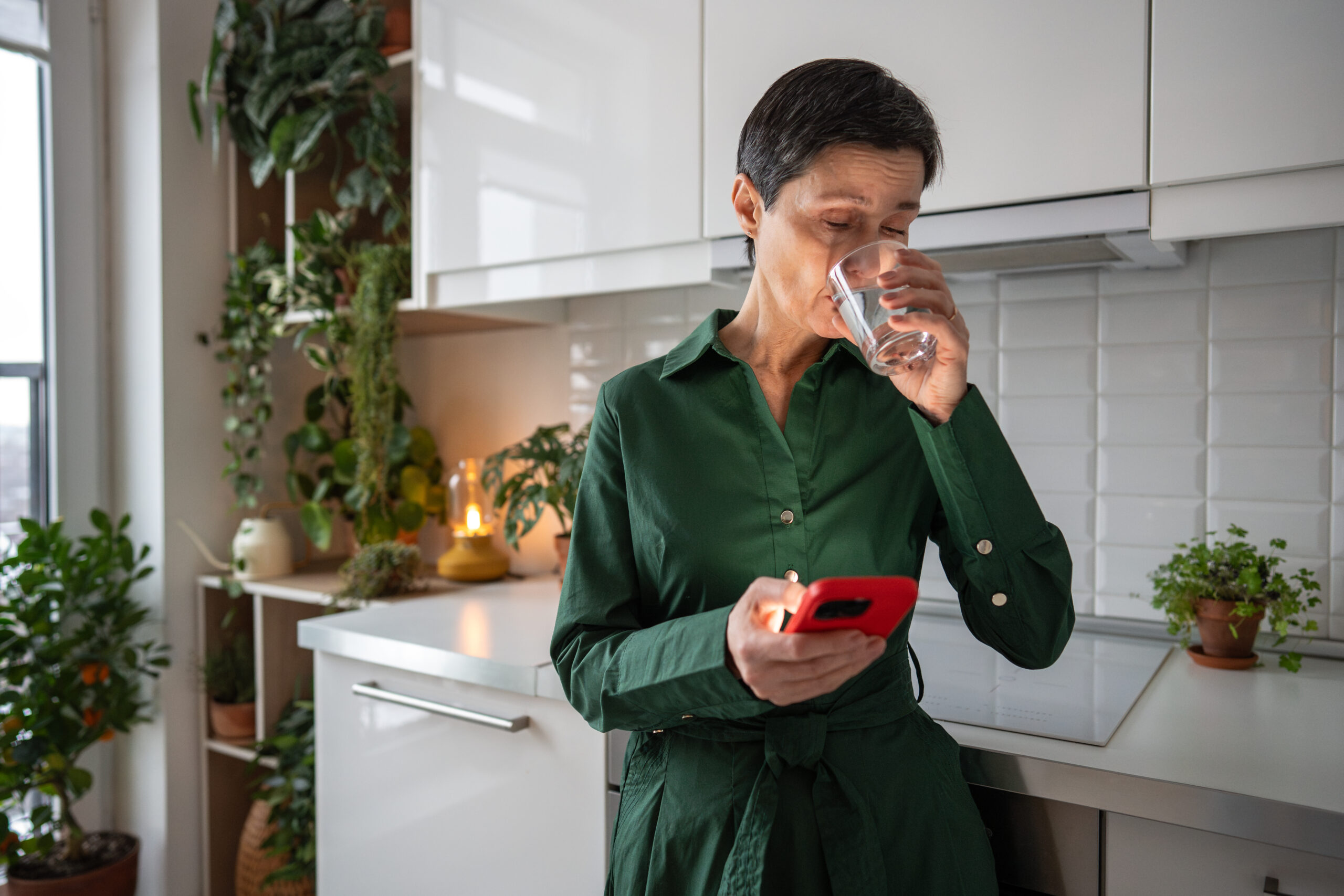Healthy habits with water. Senior woman drink water as smartphone alerts prompt hydration in morning Elderly woman drinking water following smartphone reminders and schedule. Hydration maintenance, digital health tracking, freshness wellness, routine discipline, life balance, independent living