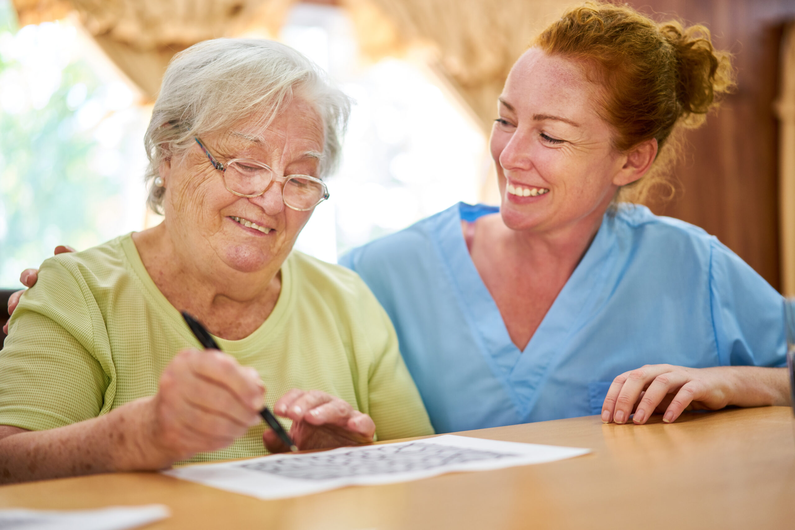 Nurse helps elderly woman with dementia solve puzzles as memory training in old people's home